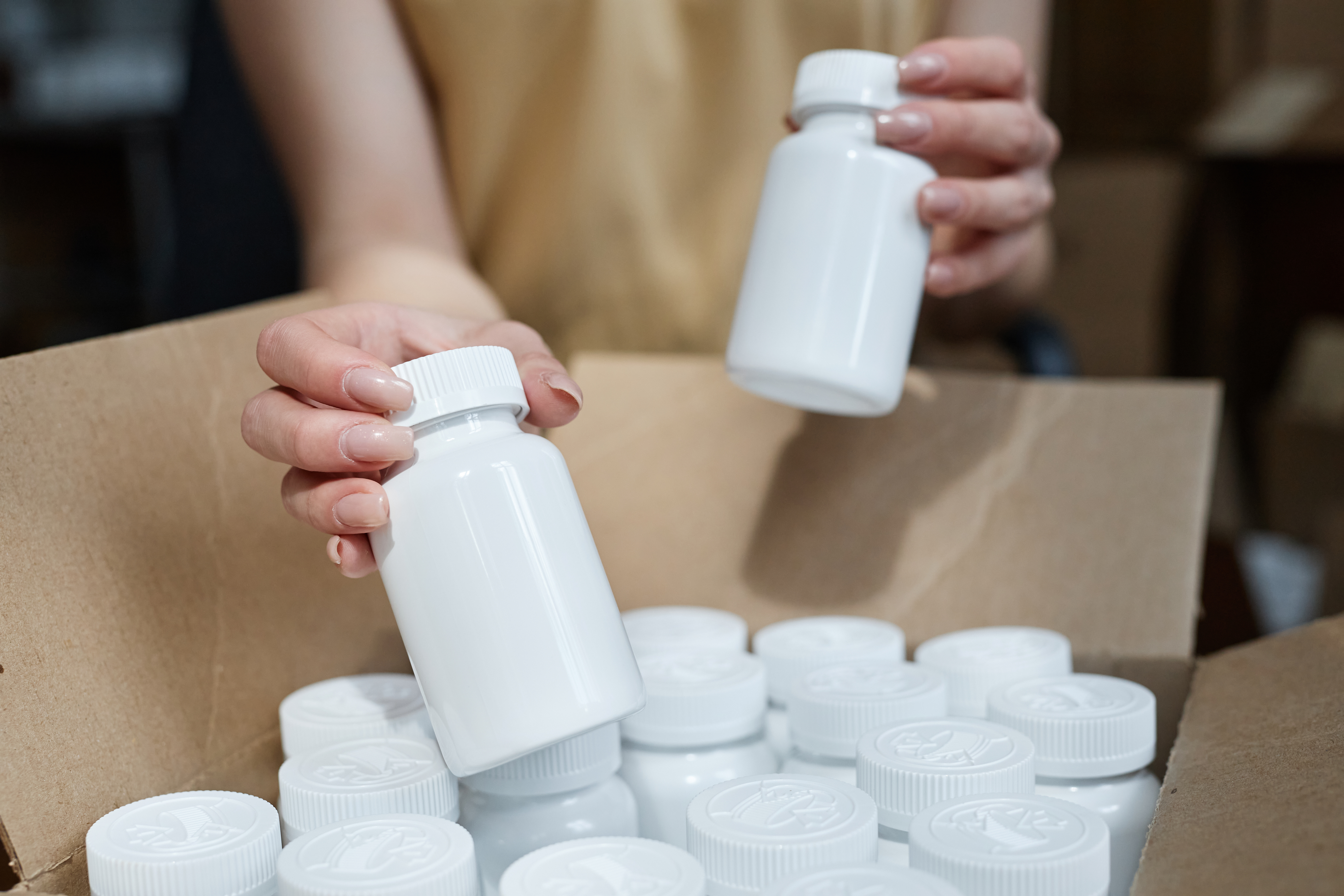 woman placing white medicine bottles in a box