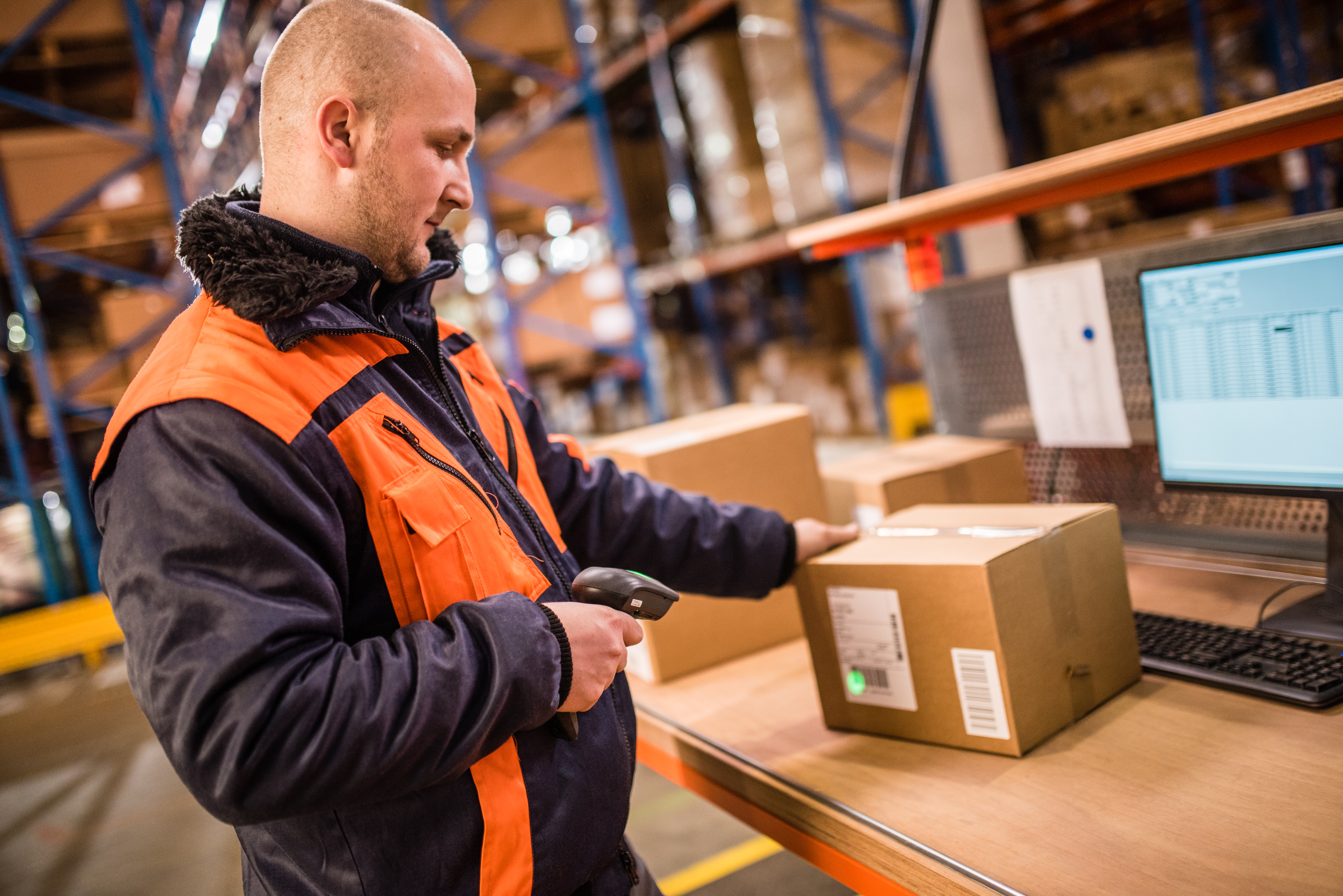 man wearing black and orange jacket scanning a package