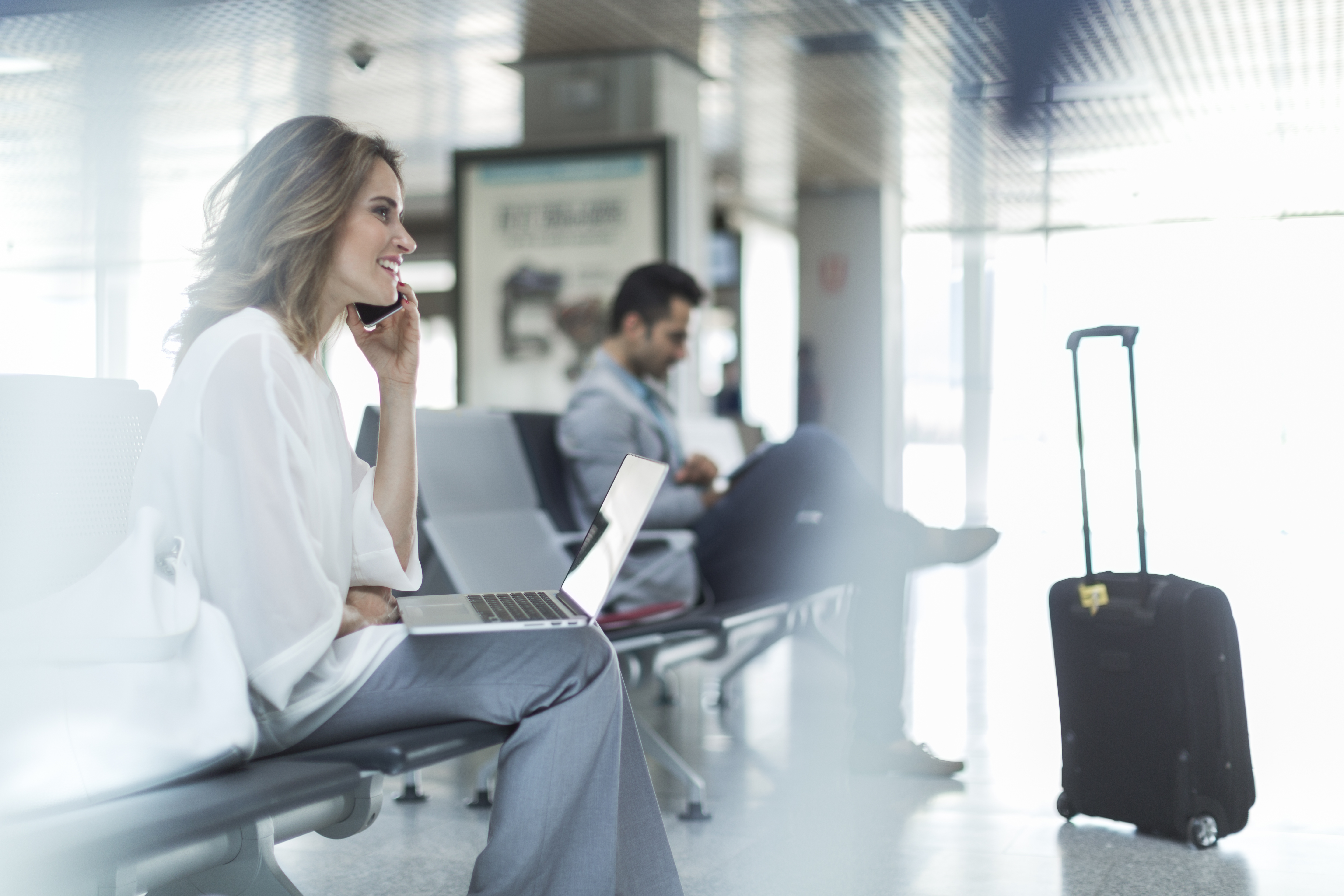 Woman working and using phone while waiting at gate